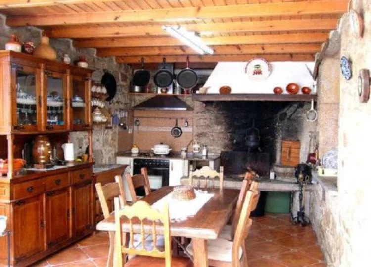 Cocina tradicional con lareira de piedra y mesa de madera
