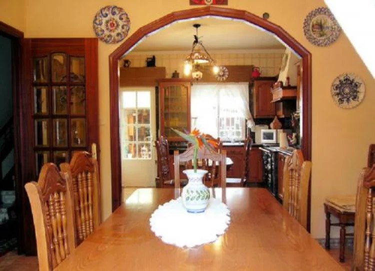 Comedor con gran mesa de madera y arco de paso