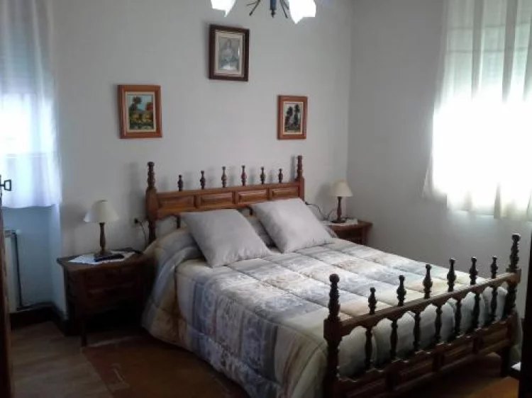 Dormitorio con cama de madera torneada y cuadros